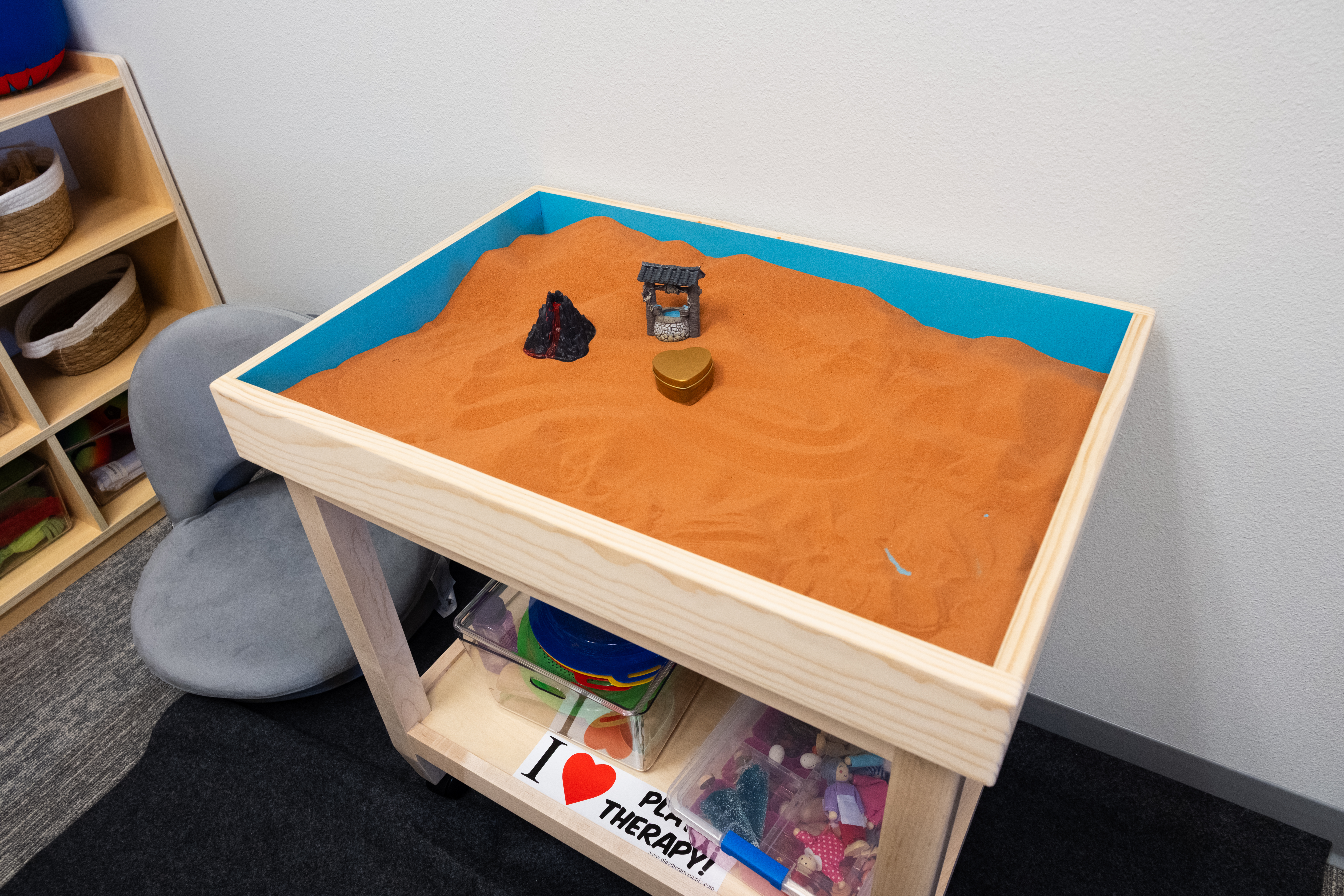 Sand tray with shelves of miniature figures.